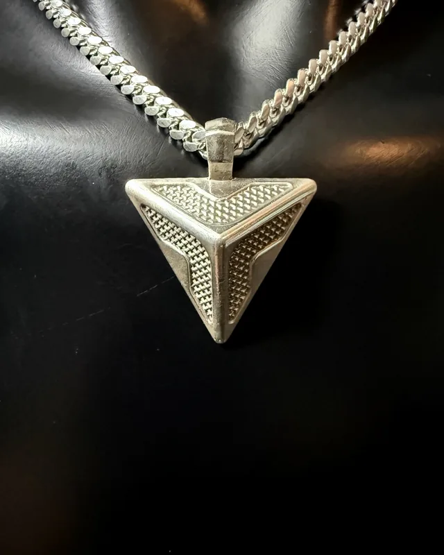 A triangular sterling silver pendant with textured inlay on a heavy curb chain